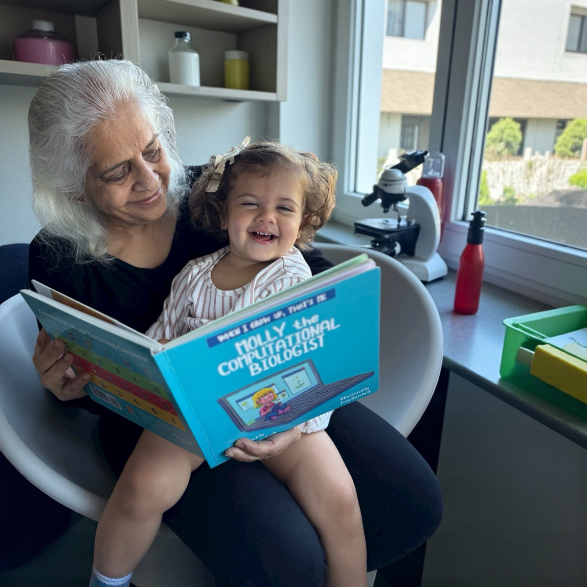 Sandhya and a young child sharing Molly the Computational Biologist